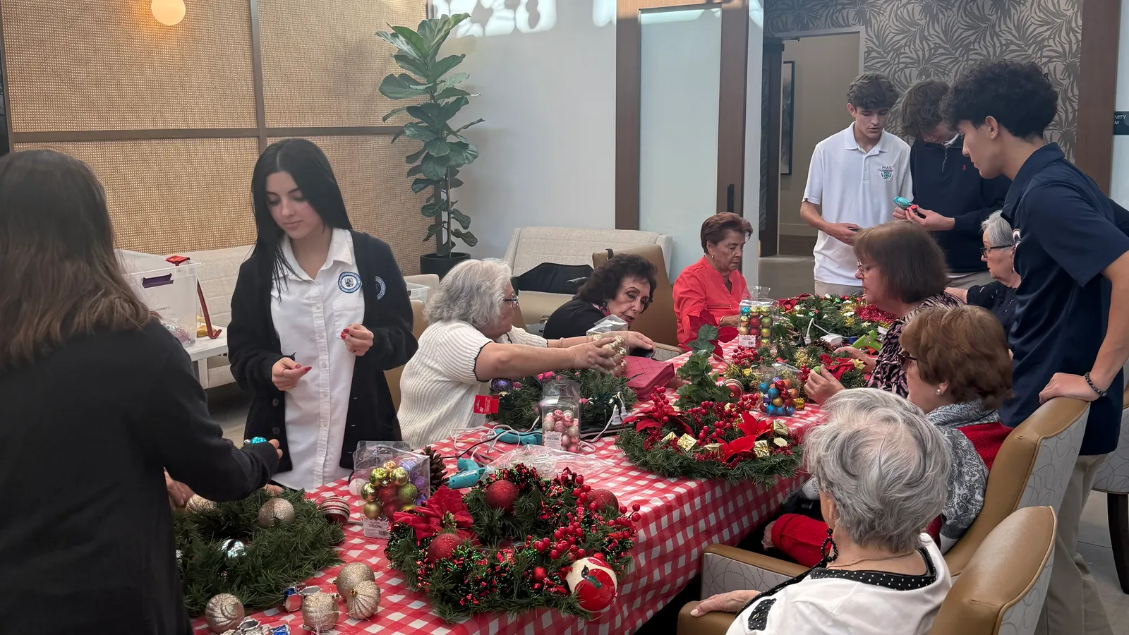 SAGE students and residents gathered around a long table making Christmas wreaths together at The Contemporary